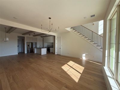 Unfurnished living room featuring beam ceiling, dark hardwood / wood-style flooring, sink, and an inviting chandelier