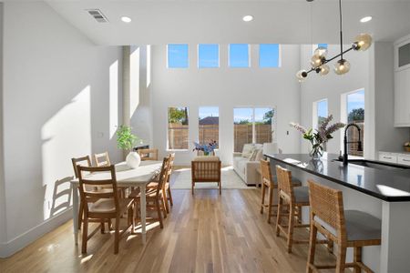 Dining area featuring sink, light hardwood / wood-style flooring, a high ceiling, and a notable chandelier