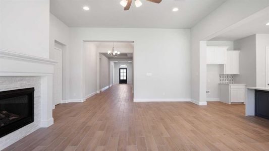 Unfurnished living room featuring ceiling fan with notable chandelier and light hardwood / wood-style floors