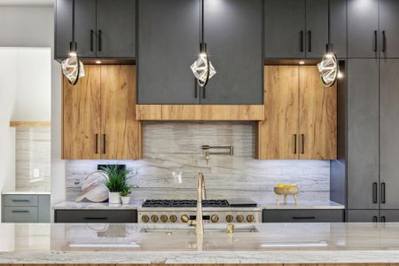 Kitchen featuring hanging light fixtures, decorative backsplash, gray cabinets, and light stone countertops