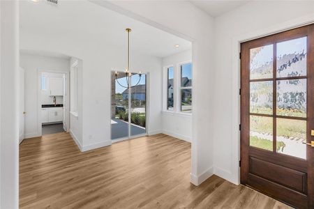 Foyer entrance with light hardwood / wood-style floors, a notable chandelier, and sink