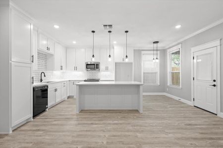 Kitchen featuring white cabinets, appliances with stainless steel finishes, a kitchen island, and hanging light fixtures