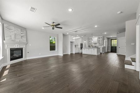 Unfurnished living room featuring ceiling fan, plenty of natural light, and dark hardwood / wood-style flooring