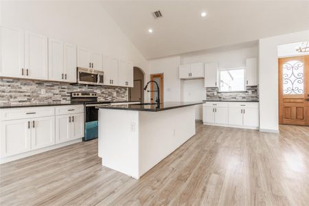 Kitchen with light hardwood / wood-style flooring, stainless steel appliances, sink, a center island with sink, and white cabinets