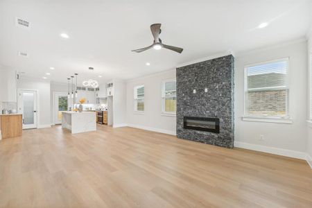 Unfurnished living room with a fireplace, ornamental molding, a healthy amount of sunlight, and ceiling fan