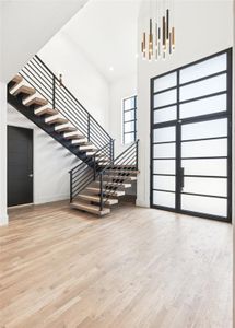 Foyer featuring light hardwood / wood-style floors and a towering ceiling