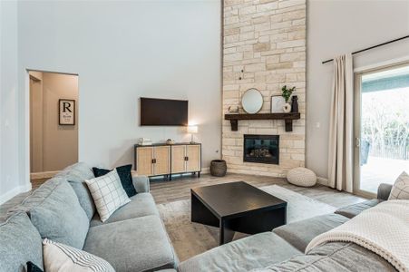 Living room with a stone fireplace, a high ceiling, and hardwood / wood-style flooring