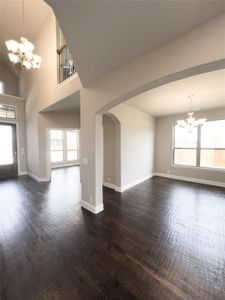 Unfurnished living room featuring a towering ceiling, dark wood-type flooring, and a healthy amount of sunlight