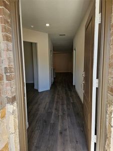 Hallway featuring dark wood-type flooring and brick wall