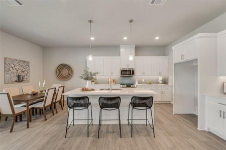 Kitchen with decorative backsplash, sink, hanging light fixtures, and an island with sink