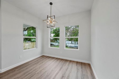 Empty room featuring an inviting chandelier and hardwood / wood-style floors