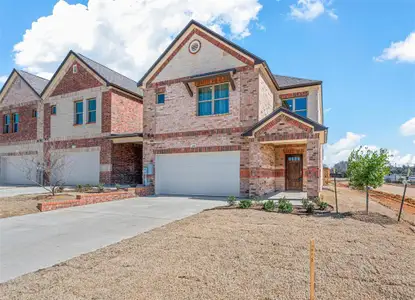 View of front of property with a garage, brick siding, and driveway