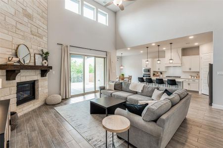 Living room with a high ceiling, ceiling fan, light hardwood / wood-style flooring, and a fireplace