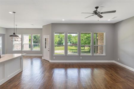 Unfurnished living room featuring ceiling fan and dark hardwood / wood-style flooring