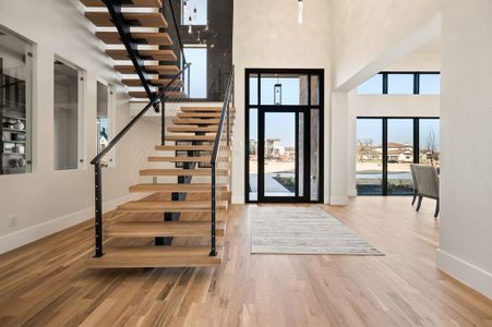 Entrance foyer with hardwood flooring, floating staircase, and a towering ceiling