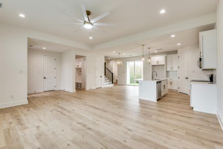 Kitchen featuring a center island with sink, white cabinets, light hardwood / wood-style floors, and decorative light fixtures