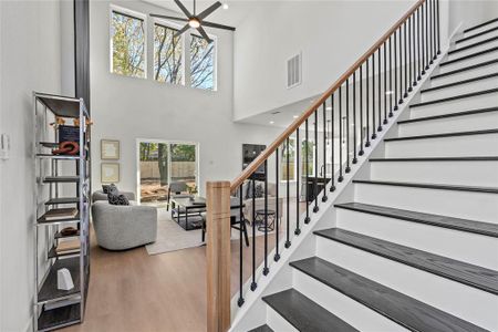 Staircase featuring hardwood / wood-style floors, ceiling fan, and a high ceiling