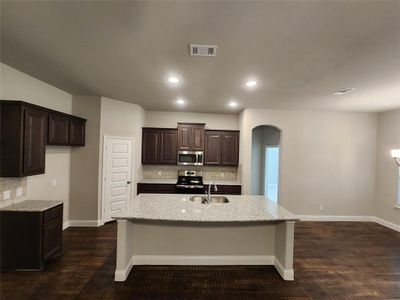 Kitchen with backsplash, appliances with stainless steel finishes, dark hardwood / wood-style floors, sink, and a kitchen island with sink