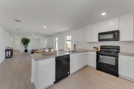 Kitchen featuring black appliances, kitchen peninsula, white cabinetry, and light hardwood / wood-style flooring