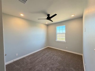 Carpeted empty room featuring ceiling fan