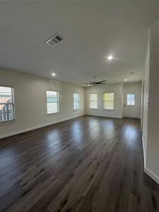 Empty room featuring dark wood-style flooring, visible vents, ceiling fan, and baseboards