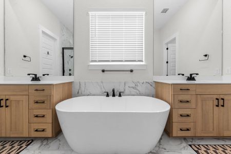 Bathroom with marble finish floor, a soaking tub, two vanities, visible vents, and a sink