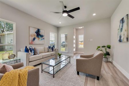 Living room with light wood-type flooring, ceiling fan, and a healthy amount of sunlight