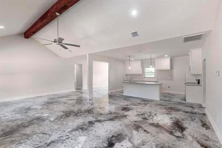 Unfurnished living room featuring vaulted ceiling with beams, ceiling fan, and sink