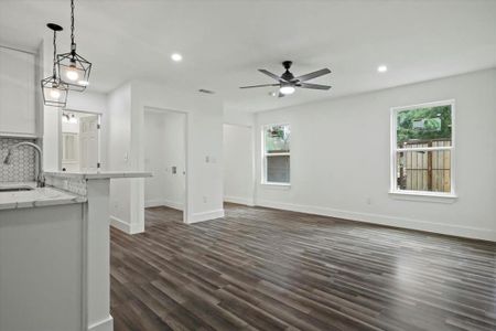 Unfurnished living room with dark hardwood / wood-style flooring, a wealth of natural light, sink, and ceiling fan