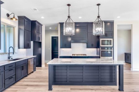 Kitchen featuring a large island, hanging light fixtures, and appliances with stainless steel finishes