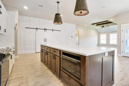 Kitchen with electric stove, light hardwood / wood-style floors, pendant lighting, a barn door, and black microwave