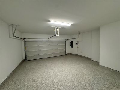 Garage featuring a garage door opener and electric panel with epoxy flooring, first floor.