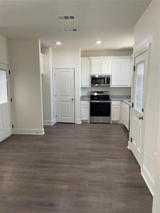 Kitchen featuring dark hardwood / wood-style floors, white cabinetry, and stove