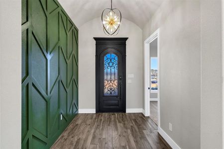 Entryway featuring lofted ceiling, wood-type flooring, and a notable chandelier