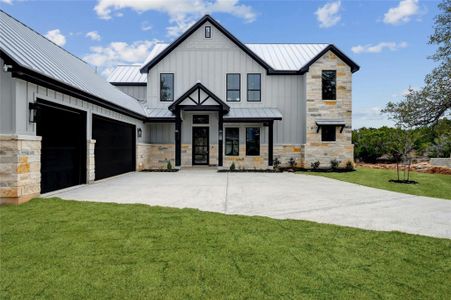 Modern farmhouse style home with board and batten siding, a standing seam roof, metal roof, a garage, and driveway