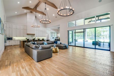 Living room with light hardwood / wood-style floors, beamed ceiling, high vaulted ceiling, and a chandelier