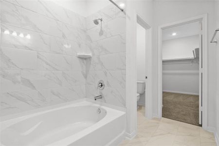 Another view of the primary bathroom featuring the oversized tub/shower combination, private toilet room, and walk-in closet.