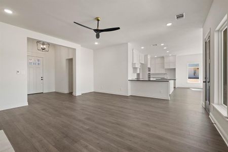 Unfurnished living room featuring ceiling fan with notable chandelier, baseboards, dark wood finished floors, and recessed lighting