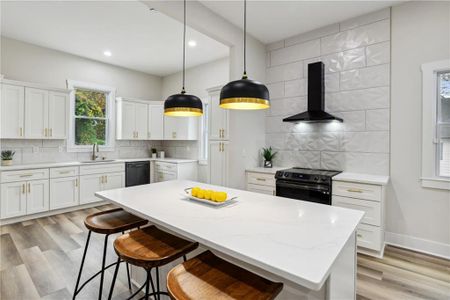 Kitchen featuring wall chimney exhaust hood, a center island, electric stove, and backsplash