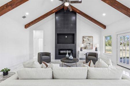 Living room with ceiling fan, tile walls, high vaulted ceiling, a fireplace, and carpet