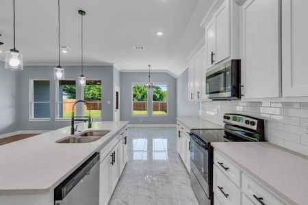 Kitchen featuring tasteful backsplash, an island with sink, stainless steel appliances, decorative light fixtures, and sink