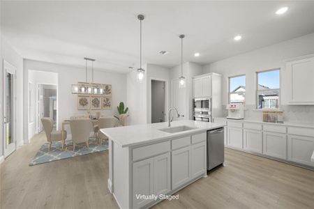 The inviting Kitchen is fresh and functional with beautiful fixtures, large island with undermount sink, white cabinetry, and stainless steel appliances.