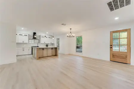 Unfurnished living room with a wealth of natural light, light hardwood / wood-style flooring, and a notable chandelier