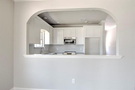 Kitchen with backsplash, white cabinets, sink, and range