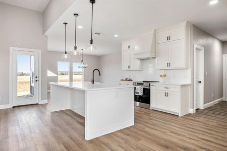 Kitchen with white cabinets, custom range hood, and stainless steel electric range