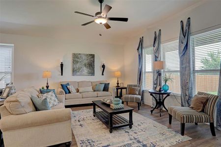 Living room with ceiling fan, ornamental molding, and hardwood / wood-style flooring