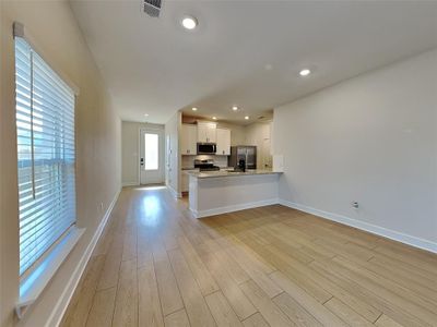 Kitchen featuring white cabinetry, kitchen peninsula, stainless steel appliances, light stone countertops, and light hardwood / wood-style flooring