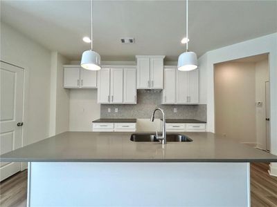 Kitchen featuring pendant lighting, sink, white cabinetry, and hardwood / wood-style flooring