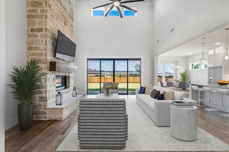 Living room featuring ceiling fan, a fireplace, a high ceiling, and light wood-type flooring