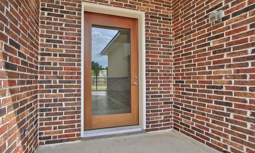 This is a bright, open-concept living space featuring high ceilings with skylights, modern tile flooring, and a clear view to the backyard through large windows and glass doors. A contemporary staircase leads to additional space above.